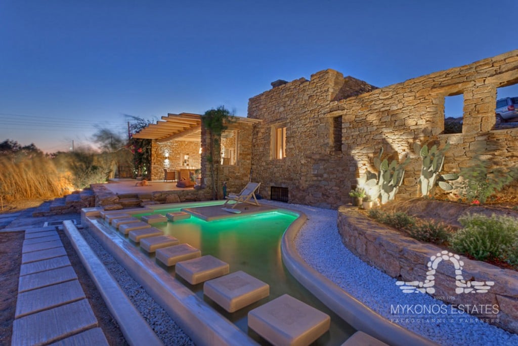 Stone villa and lit pool at dusk at Villa Lavinia in Chalara, Mykonos