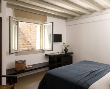 Bedroom with stone-framed window at Villa Ammolite, Kounoupas, Mykonos