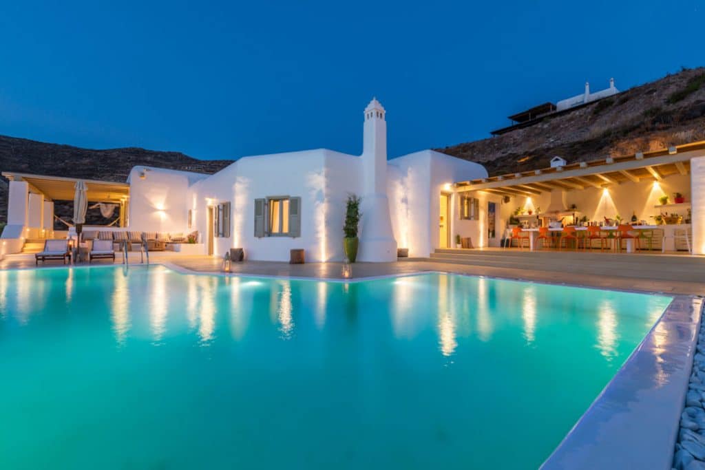 Pool and white villa lit at dusk at Ftelia Boheme in Ftelia, Mykonos