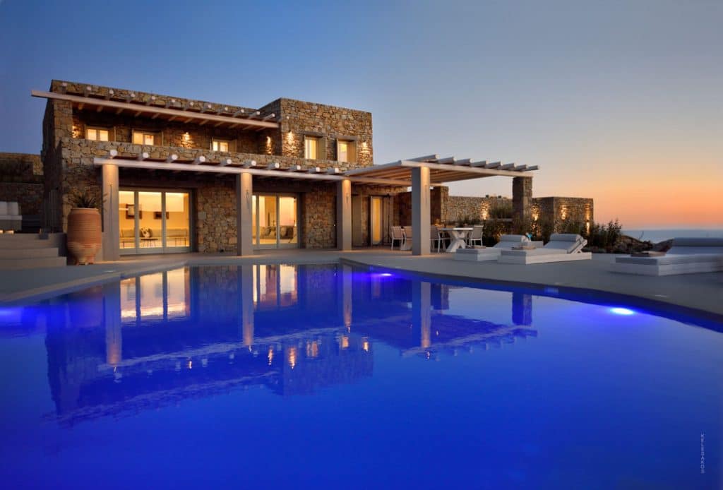 Stone villa and pool lit at dusk at Villa Moonstone in Kounoupas, Mykonos