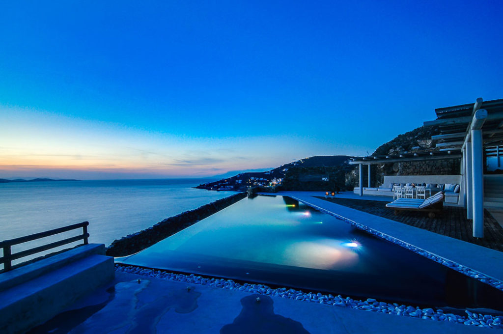 Infinity pool at dusk with coastline at Villa Morpheus in Agios Ioannis, Mykonos