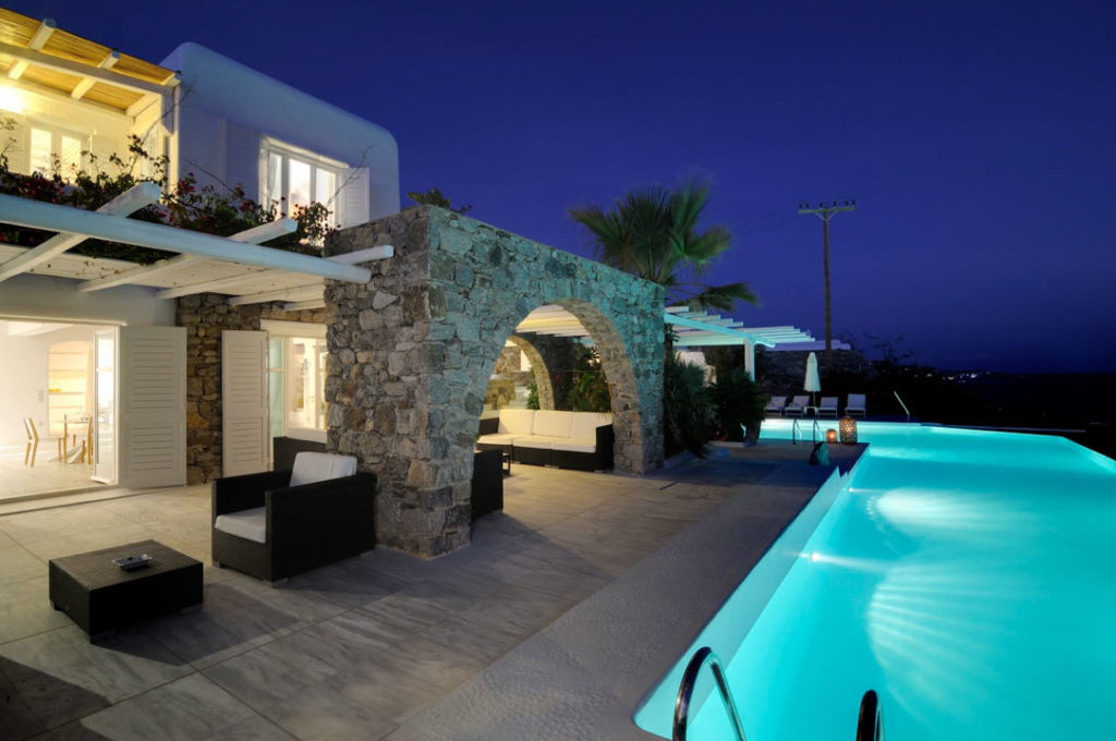 Lit pool and stone arch at twilight at Villa Megalia in Aleomandra, Mykonos