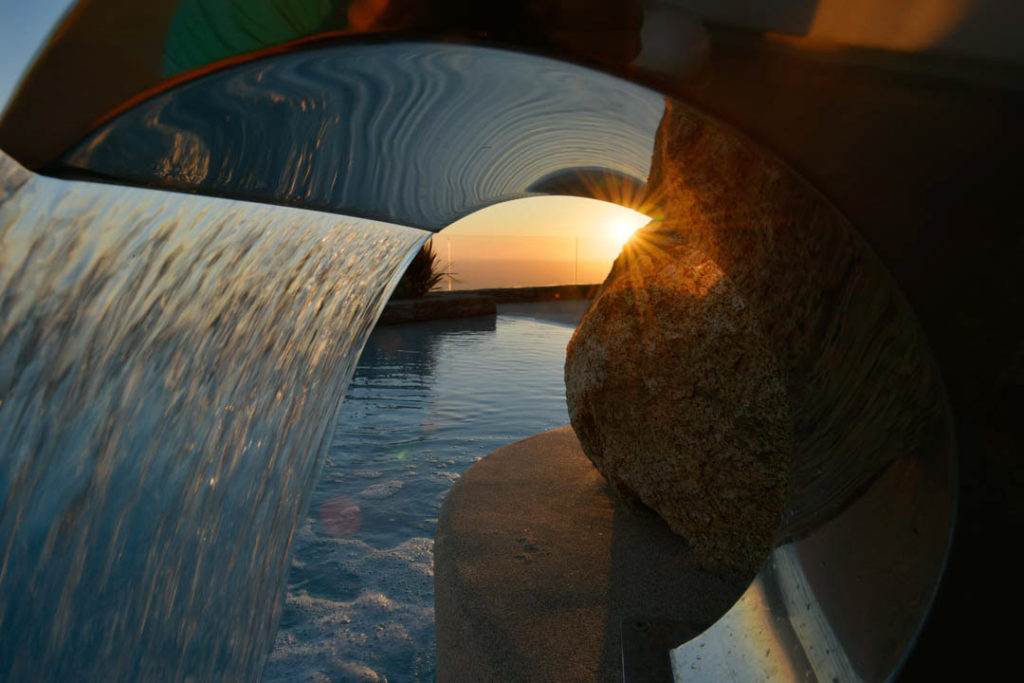 Water feature pouring into the pool at dusk at Oblivia Retreat, Kounoupas, Mykonos
