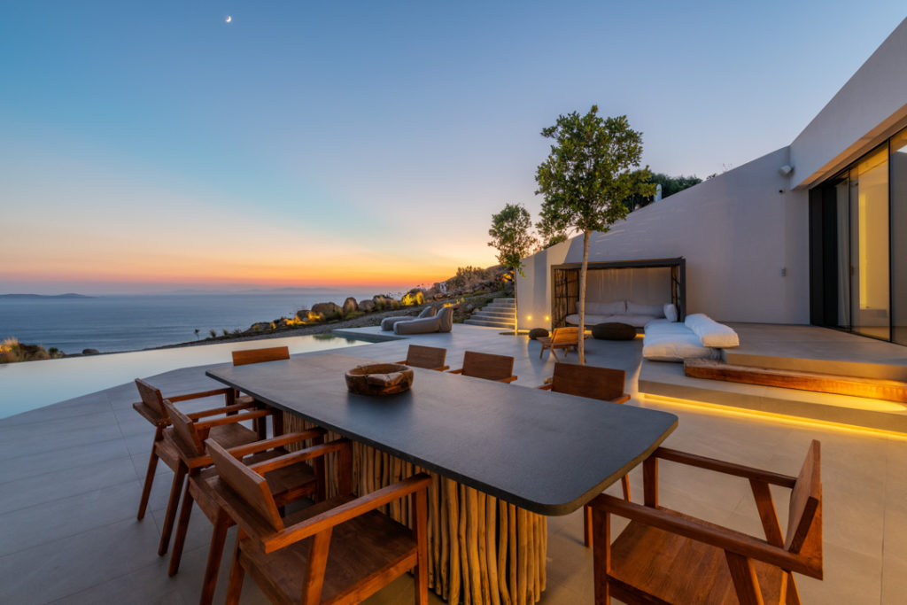 Outdoor dining table on the terrace at sunset with sea view at Dove Luxury Estate, Agios Stefanos, Mykonos