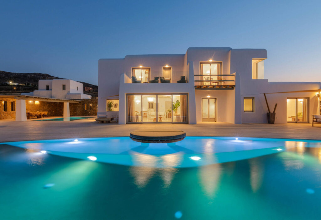 Villa Mati's white Cycladic house and illuminated pool at dusk, Ftelia, Mykonos