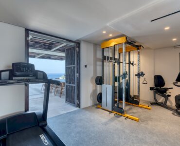 Indoor gym with treadmill and open view towards the sea at Aether Private Retreat - Grand Villa, Aleomandra, Mykonos