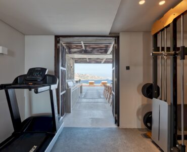 Indoor gym with treadmill and open view towards the sea at Aether Private Retreat - Grand Villa, Aleomandra, Mykonos