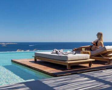 Guest relaxing on a pool sunbed overlooking the sea at Aether Private Retreat - Grand Villa, Aleomandra, Mykonos