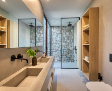 En-suite bathroom with round mirror and stone-finish vanity at Aether Private Retreat - Grand Villa, Aleomandra, Mykonos