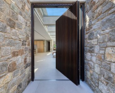 Entrance with pivot door set in natural stone walls at Aether Private Retreat - Ground Floor, Aleomandra, Mykonos