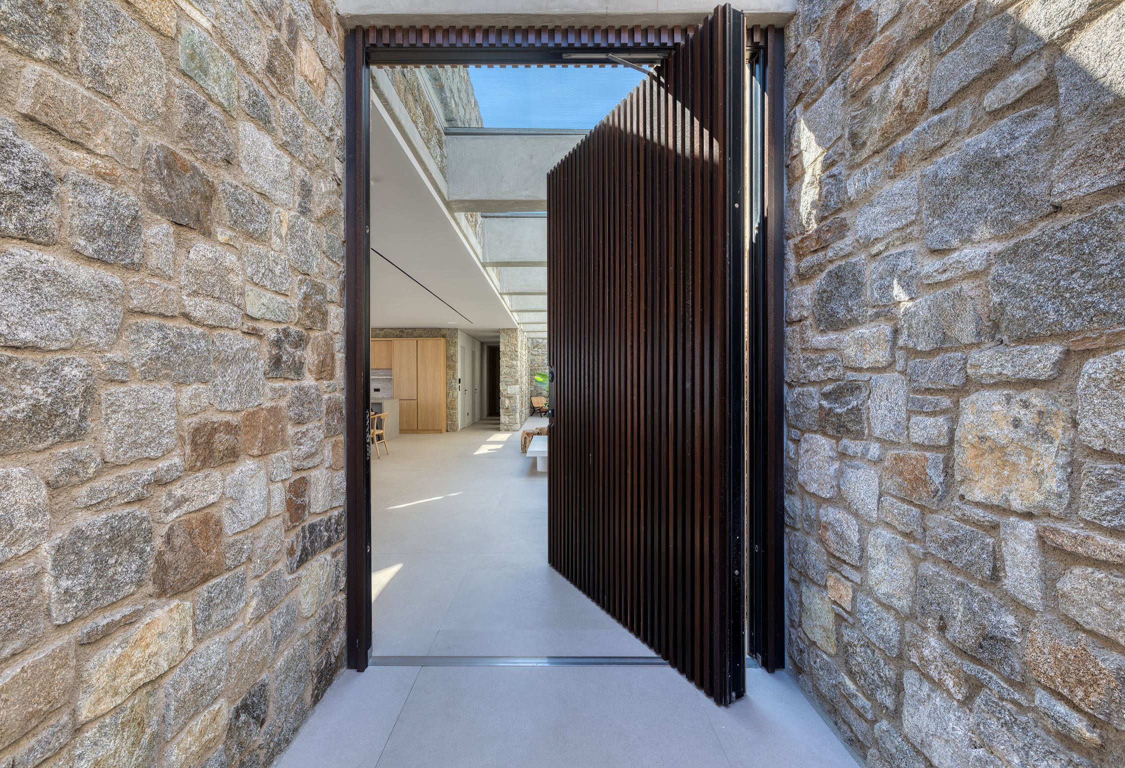 Entrance with pivot door set in natural stone walls at Aether Private Retreat - Ground Floor, Aleomandra, Mykonos