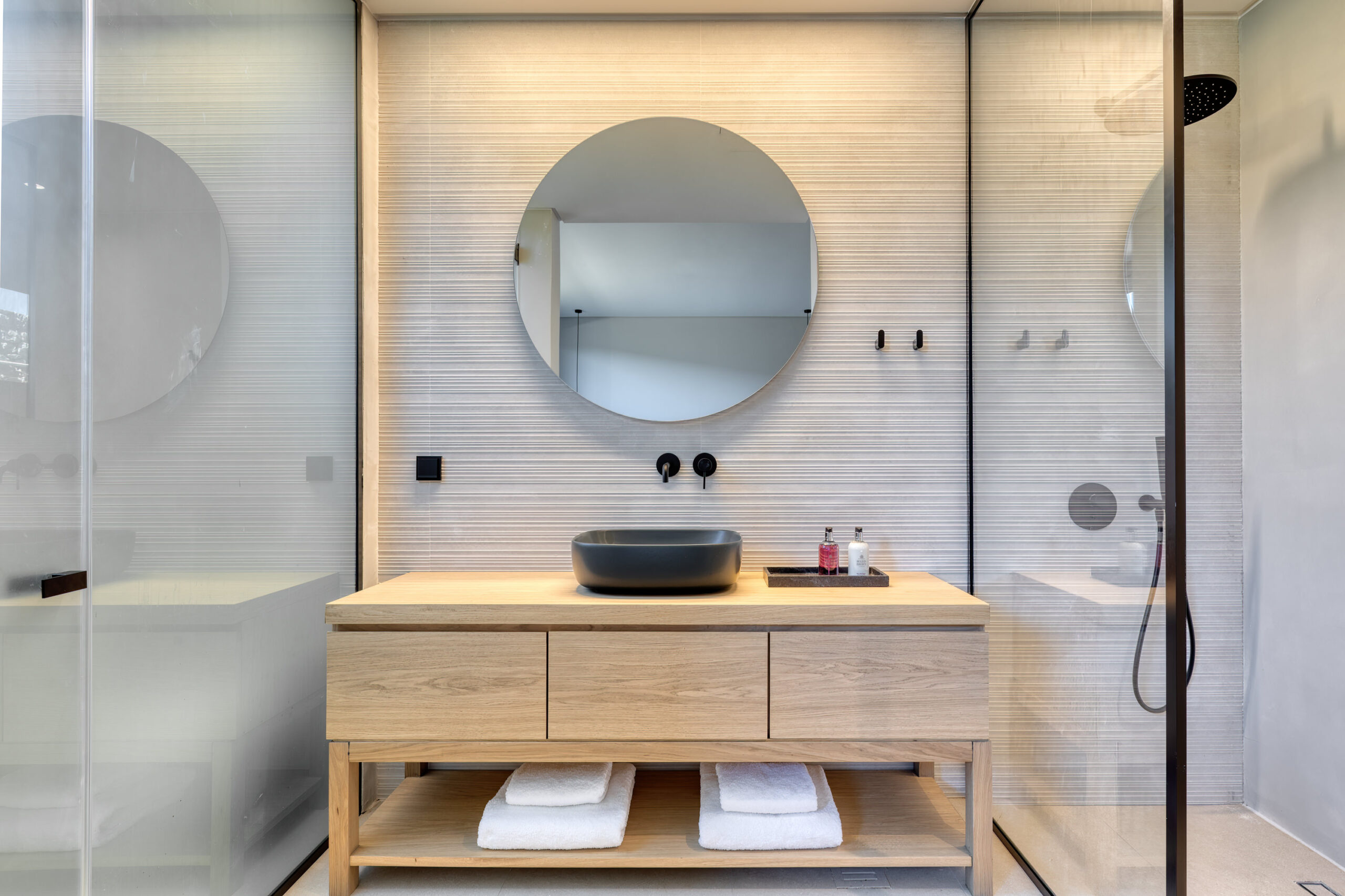 En-suite bathroom with round mirror and stone-finish vanity at Aether Private Retreat - Ground Floor, Aleomandra, Mykonos