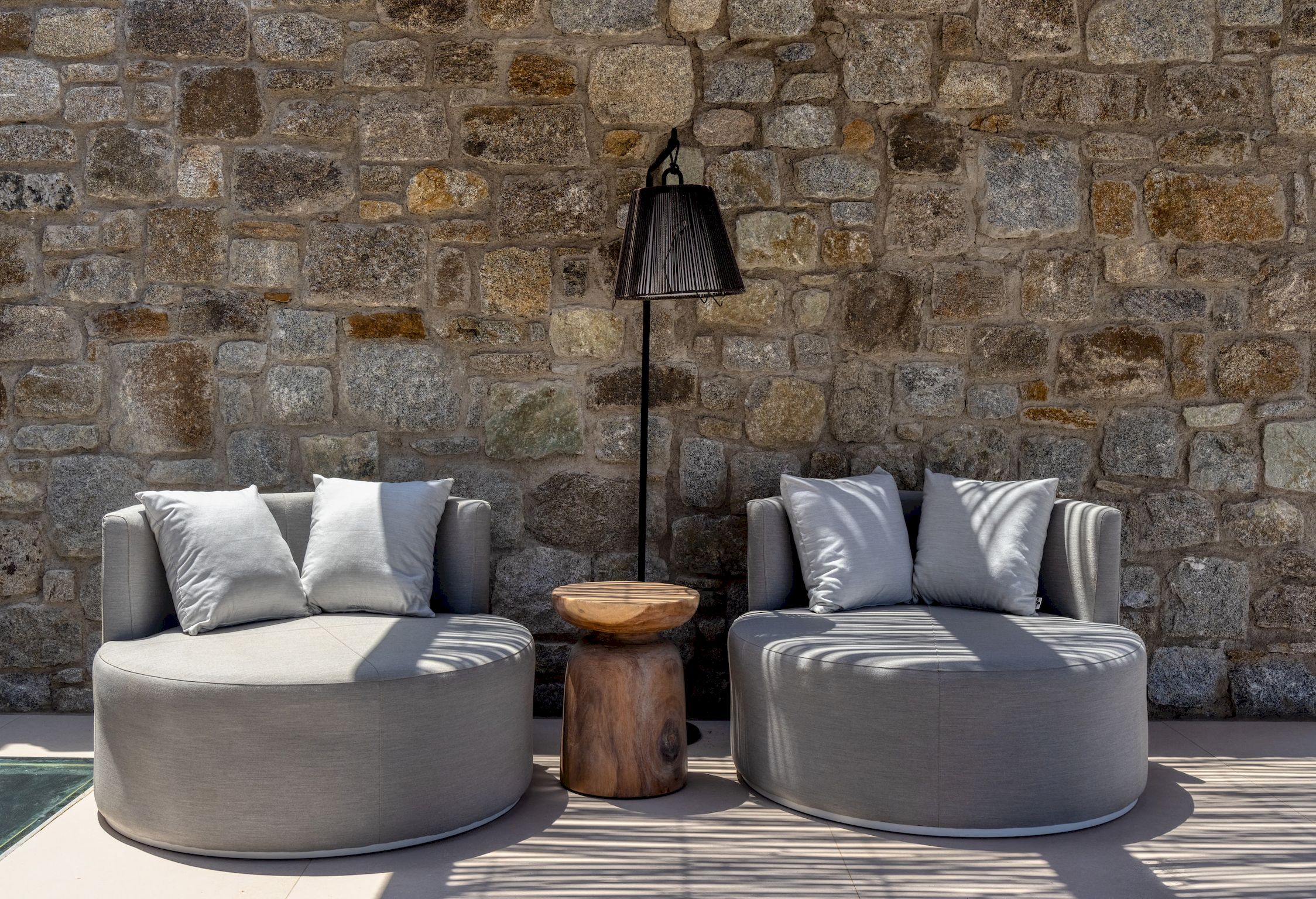 Round lounge chairs against a natural stone wall at Aether Private Retreat - Ground Floor, Aleomandra, Mykonos