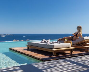 Guest relaxing on a pool sunbed overlooking the sea at Aether Private Retreat - Ground Floor, Aleomandra, Mykonos