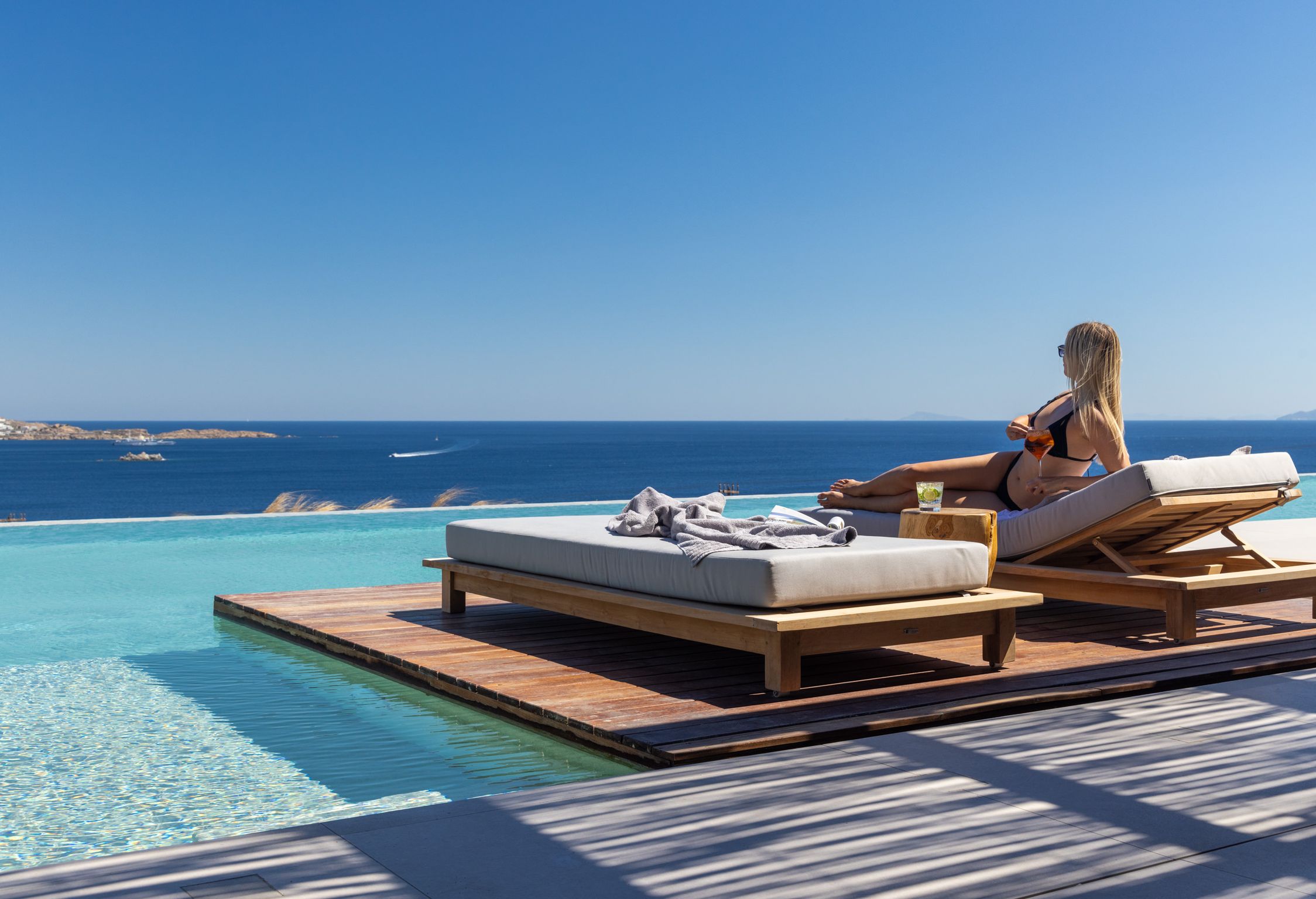 Guest relaxing on a pool sunbed overlooking the sea at Aether Private Retreat - Ground Floor, Aleomandra, Mykonos