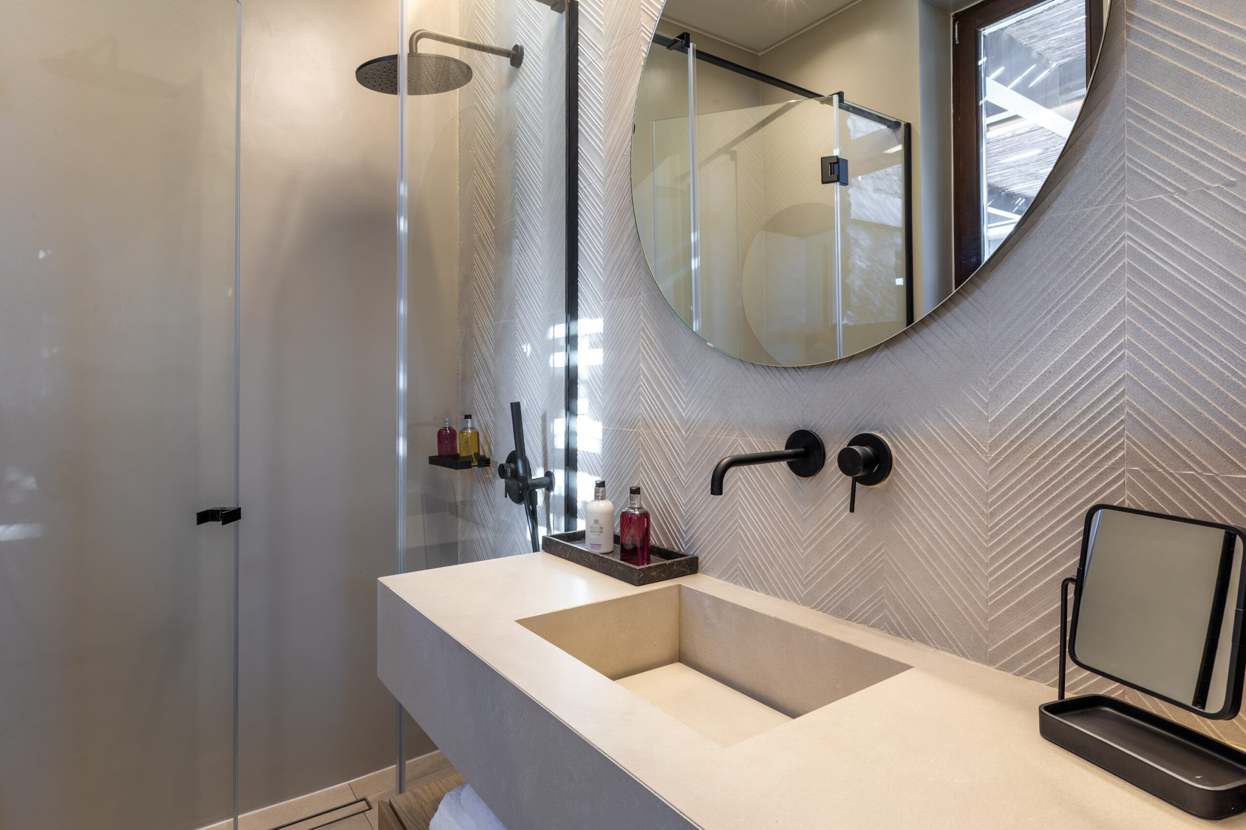 En-suite bathroom with round mirror and stone-finish vanity at Aether Private Retreat - Ground Floor, Aleomandra, Mykonos