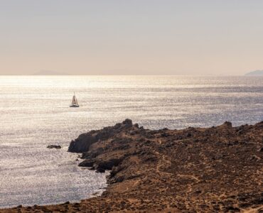 Sunset over the Aegean Sea with a sailing boat near the rocky shore at Aether Private Retreat - Ground Floor, Aleomandra, Mykonos
