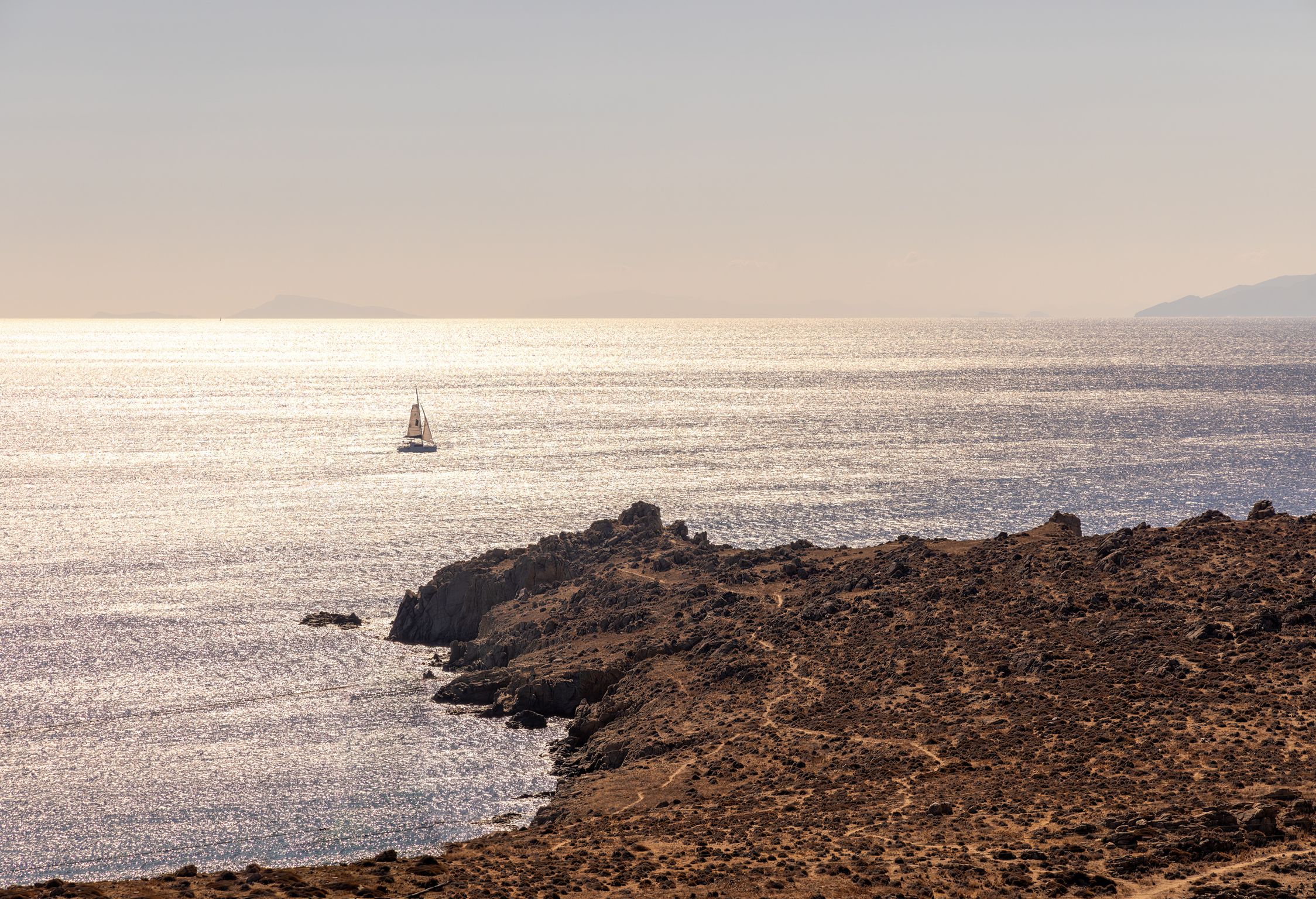 Sunset over the Aegean Sea with a sailing boat near the rocky shore at Aether Private Retreat - Ground Floor, Aleomandra, Mykonos
