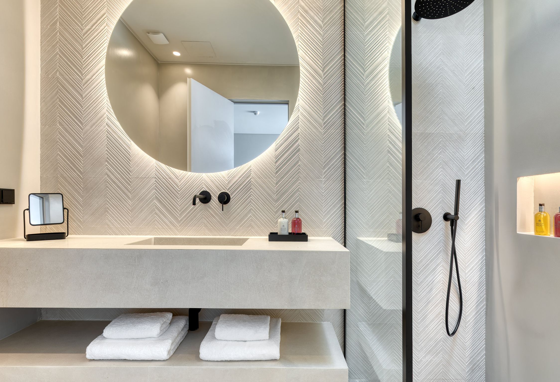 En-suite bathroom with round mirror and stone-finish vanity at Aether Private Retreat - Upper Floor, Aleomandra, Mykonos