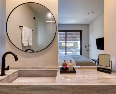 En-suite bathroom with round mirror and stone-finish vanity at Aether Private Retreat - Upper Floor, Aleomandra, Mykonos