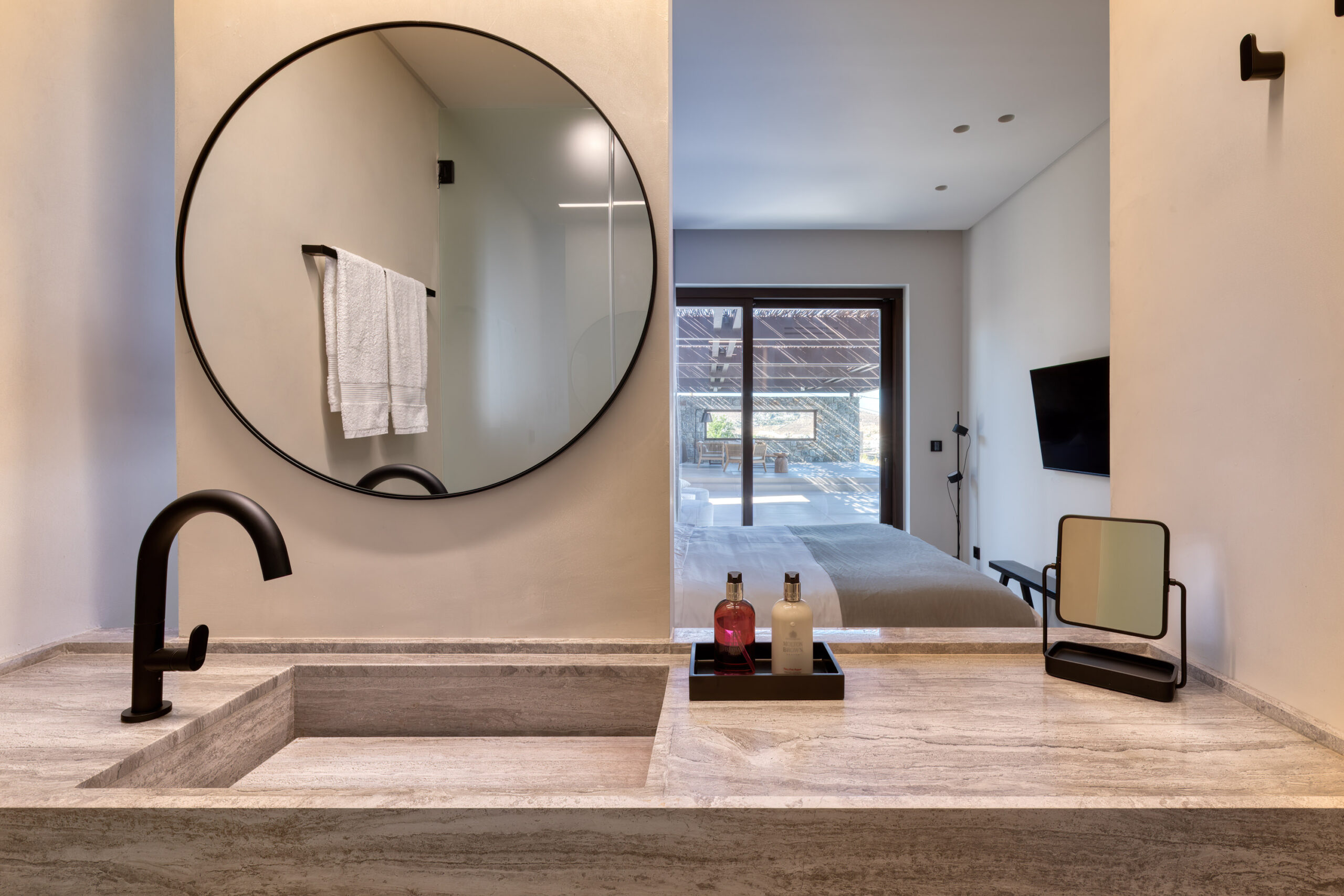 En-suite bathroom with round mirror and stone-finish vanity at Aether Private Retreat - Upper Floor, Aleomandra, Mykonos