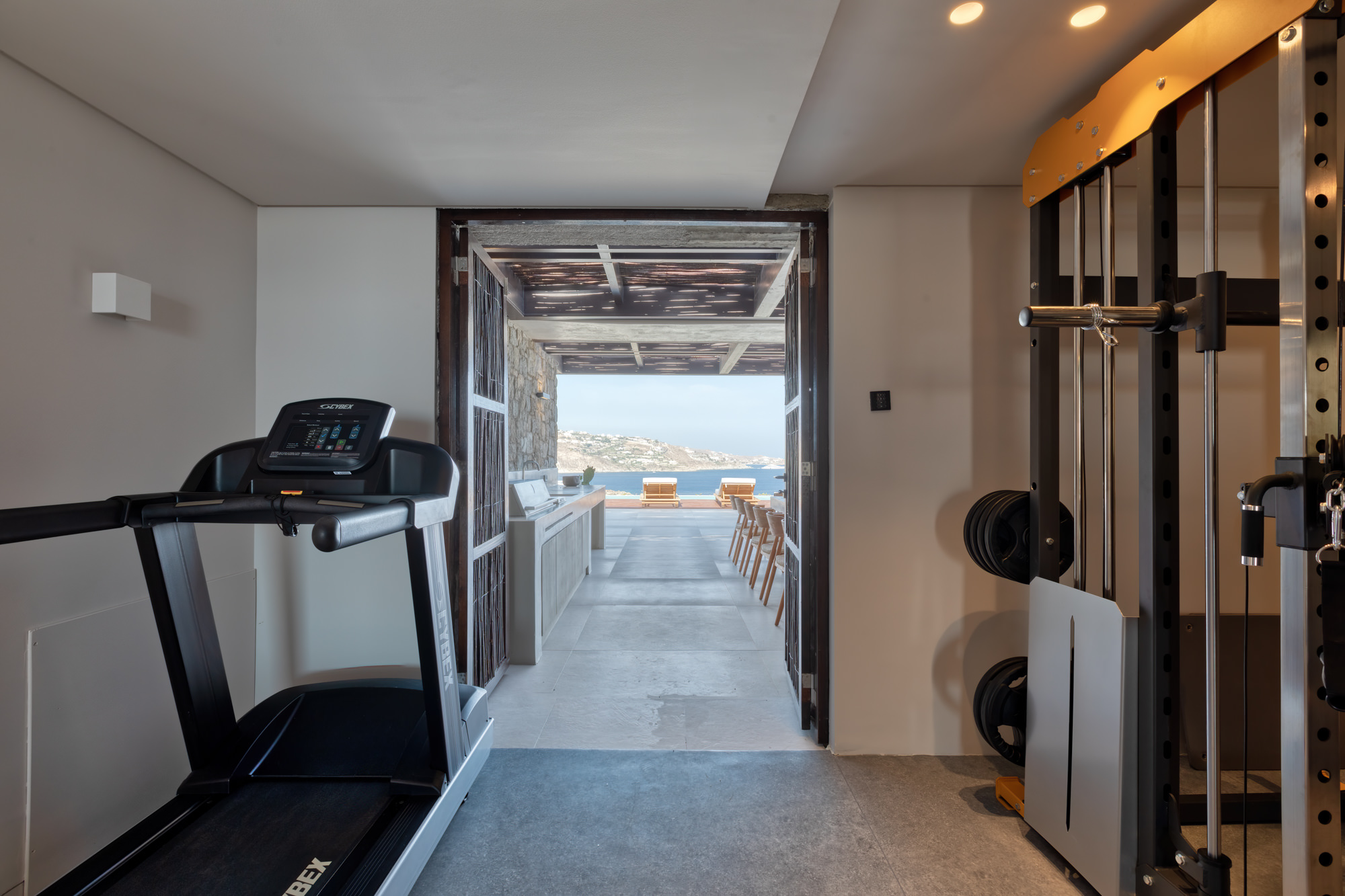 Indoor gym with treadmill and open view towards the sea at Aether Private Retreat - Upper Floor, Aleomandra, Mykonos