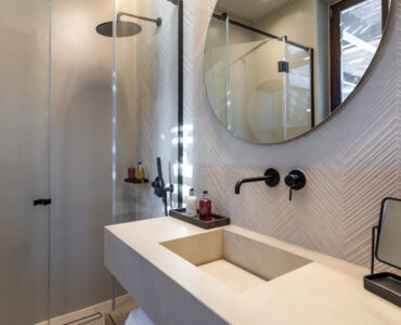 En-suite bathroom with round mirror and stone-finish vanity at Aether Private Retreat - Upper Floor, Aleomandra, Mykonos