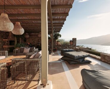 Stone patio with lounge seating and sea views at Bali Sea Front Villa in Ftelia, Mykonos