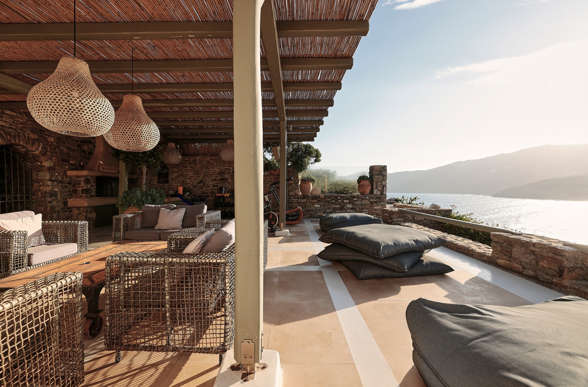 Stone patio with lounge seating and sea views at Bali Sea Front Villa in Ftelia, Mykonos