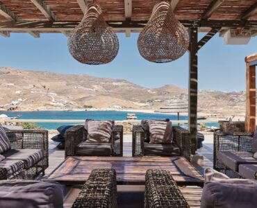 Stone patio with lounge seating and sea views at Bali Sea Front Villa in Ftelia, Mykonos