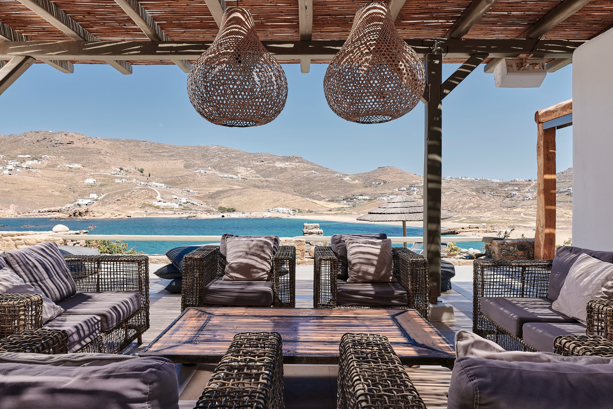 Stone patio with lounge seating and sea views at Bali Sea Front Villa in Ftelia, Mykonos