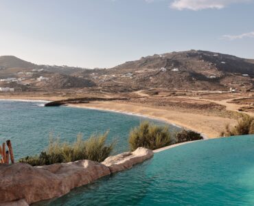 Infinity pool with sun loungers and views over Ftelia bay (view 11) at Bali Sea Front Villa in Ftelia, Mykonos