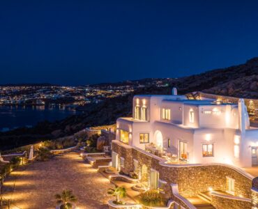 Illuminated villa and terraces with the lights of Mykonos Town at night – Grand Kanalia estate for sale in Kanalia, Mykonos