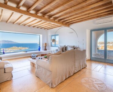 Living room with timber ceiling and panoramic sea window – Grand Kanalia estate for sale in Kanalia, Mykonos