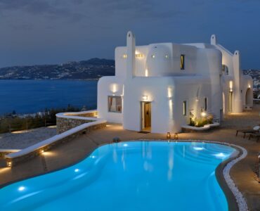 Infinity pool and illuminated villa at blue hour – Grand Kanalia estate for sale in Kanalia, Mykonos