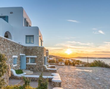 Whitewashed villa and stone terraces at sunset – Grand Kanalia estate for sale in Kanalia, Mykonos
