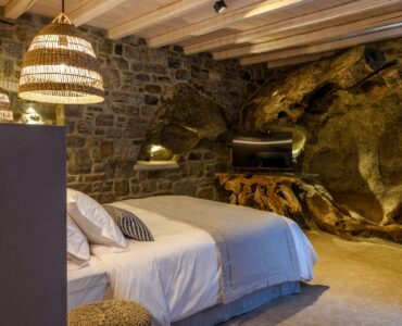 Bedroom with natural rock wall at Muse Mansion in Agios Lazaros, Mykonos
