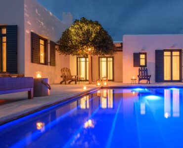 Villa and lit pool at dusk at Platinum Senior Villa in Kalafatis, Mykonos