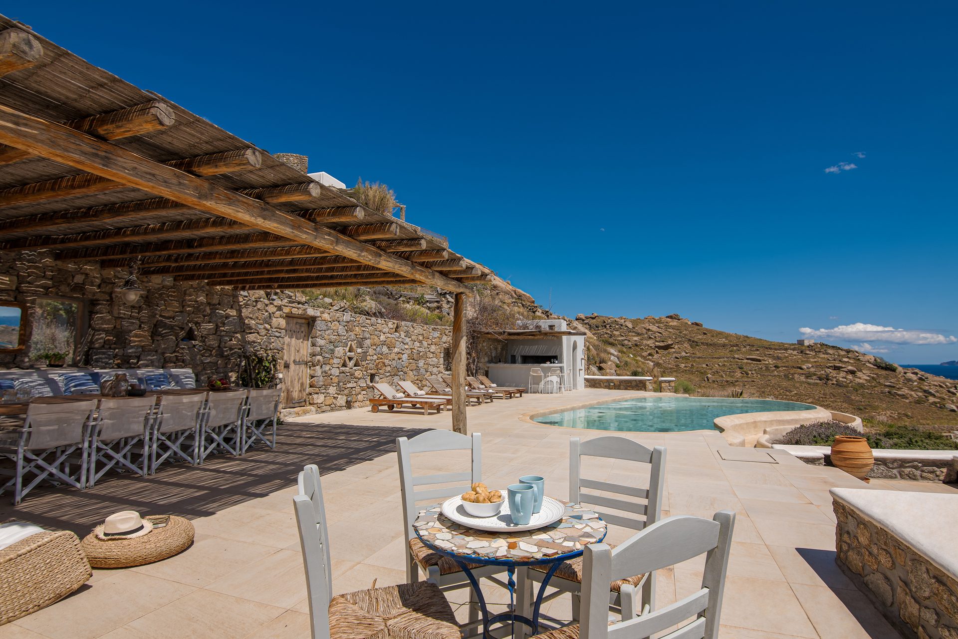 Pergola-covered outdoor dining with sea view at Tranquil Villa 5 in Kalafatis, Mykonos