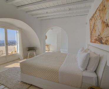 Bedroom with arched window and artwork at Villa Alkioni in Agios Lazaros, Mykonos