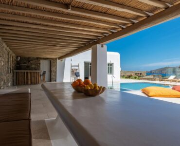 Shaded pergola with outdoor bar and pool views at Villa Aloni in Ftelia, Mykonos