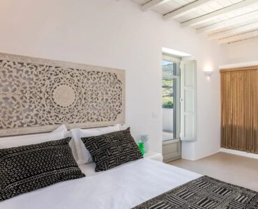 Double bedroom with carved wooden headboard at Villa Aloni in Ftelia, Mykonos