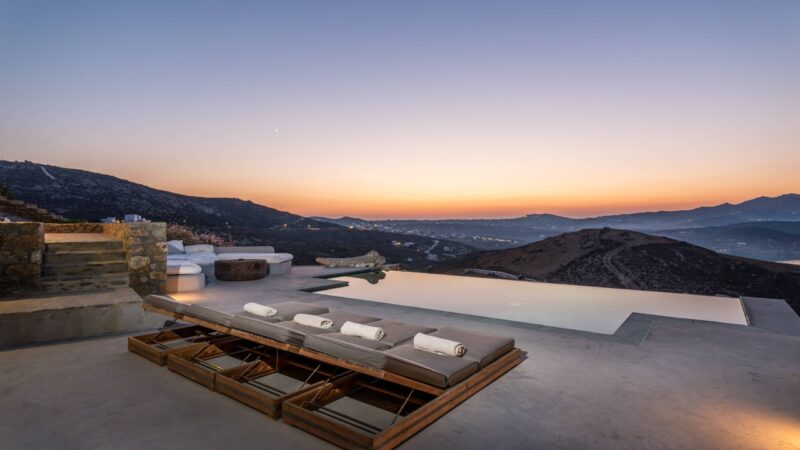 Sunset over the infinity pool and sun loungers at Villa Amra in Ftelia, Mykonos