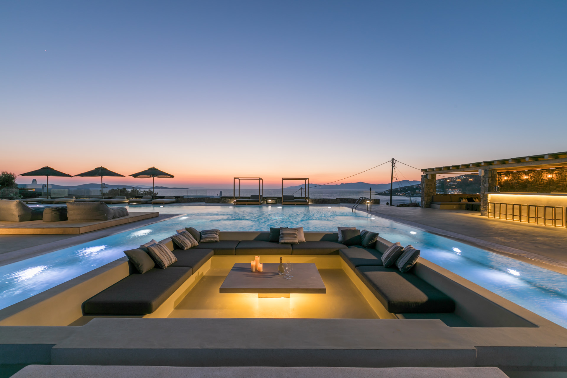 Pool lounge and pool bar at dusk at Villa Arion in Aleomandra, Mykonos