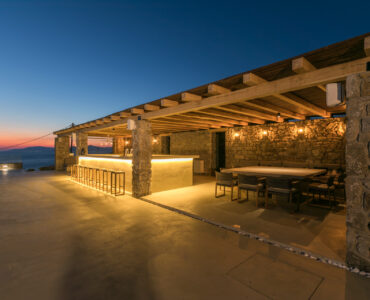 Pool bar and outdoor dining at dusk at Villa Arion in Aleomandra, Mykonos