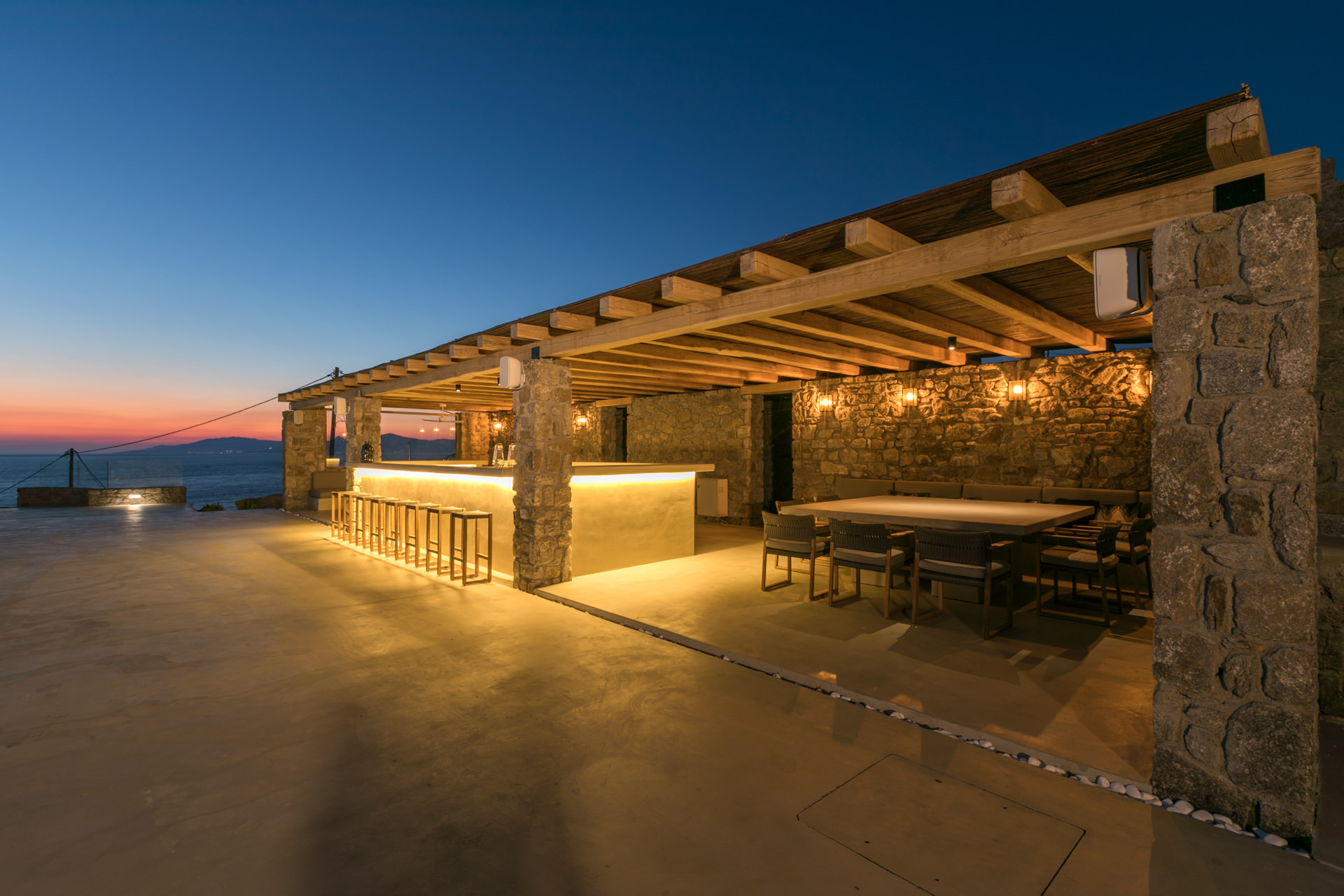 Pool bar and outdoor dining at dusk at Villa Arion in Aleomandra, Mykonos