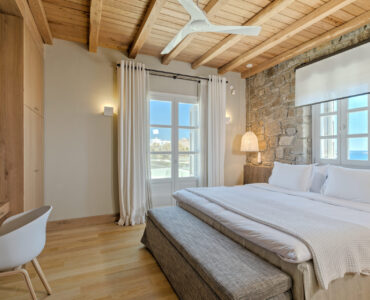 Master bedroom with stone wall at Villa Arion in Aleomandra, Mykonos