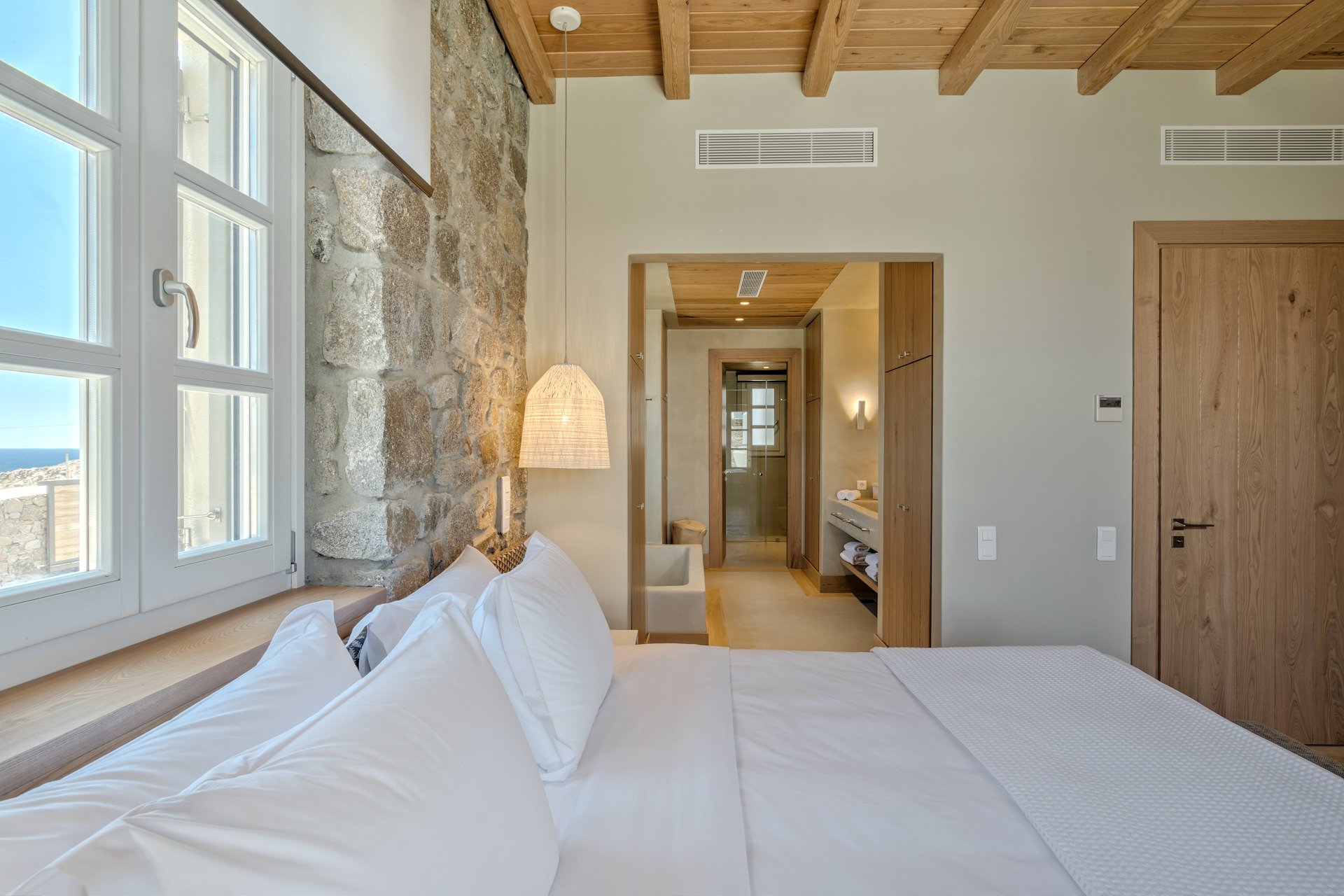 Master bedroom with sea-view windows at Villa Arion in Aleomandra, Mykonos
