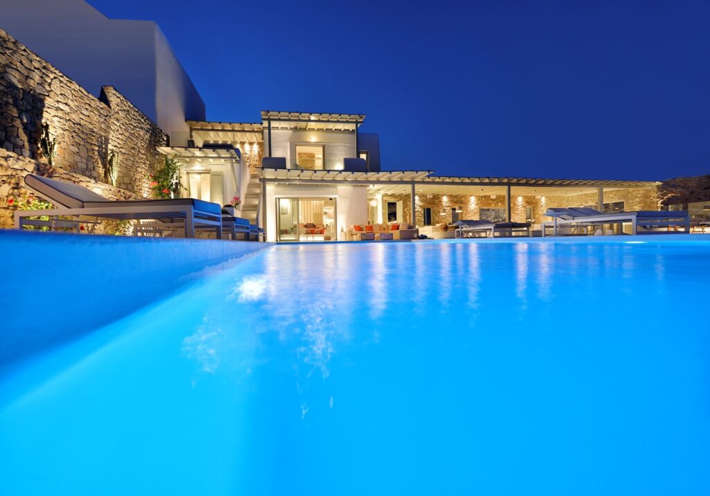 Pool lit at dusk in front of the main house at Villa Dedalia in Elia, Mykonos