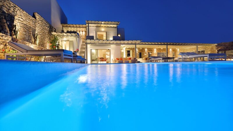 Pool lit at dusk in front of the main house at Villa Dedalia in Elia, Mykonos